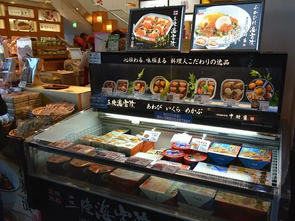 Japanese deli display with dish replicas and price tags in front of packaged products
