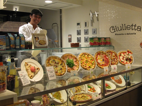 Pizzeria kitchen show with pizzaiolo handcrafting pizzas in front of guests
