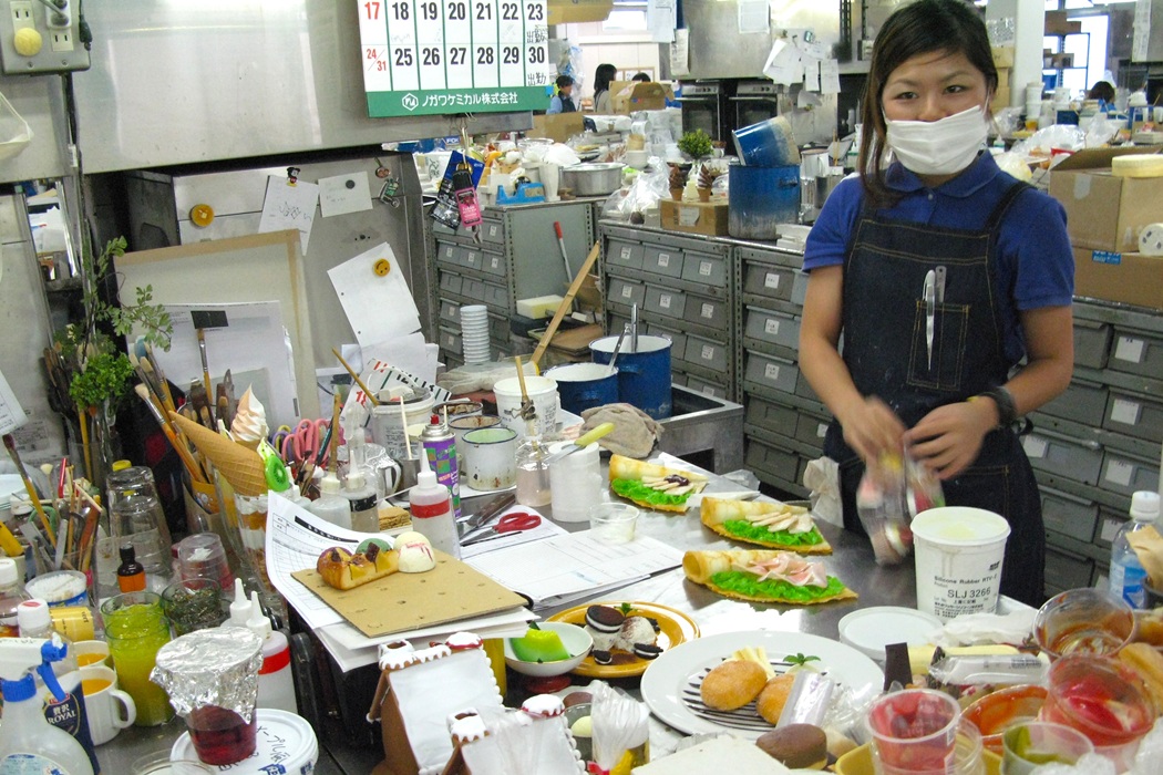 Japanese food replica artisan checking the finished dessert replica against the original dish photo for accuracy