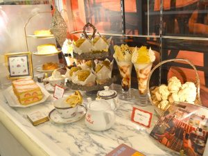 Café showcase styled as cozy tea-time table with food replicas attracting visitors