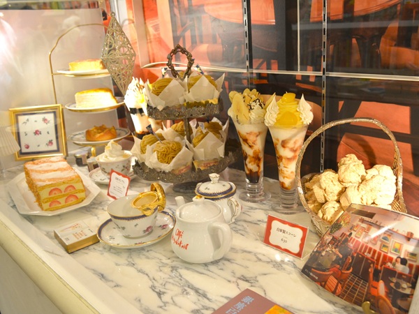 Café showcase styled as cozy tea-time table with food replicas attracting visitors