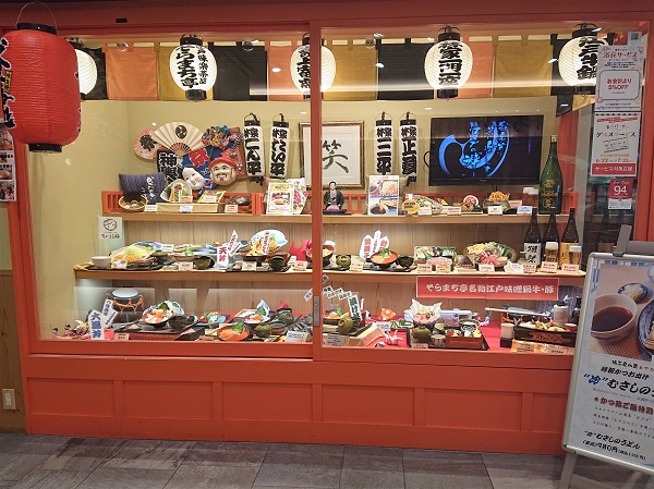 Japanese restaurant showcase with food replicas and traditional décor such as masks, dolls, fans and lanterns