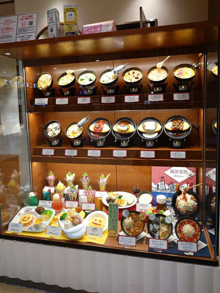 Restaurant window displays with children’s menu food replicas on a lower shelf and kids’ gifts