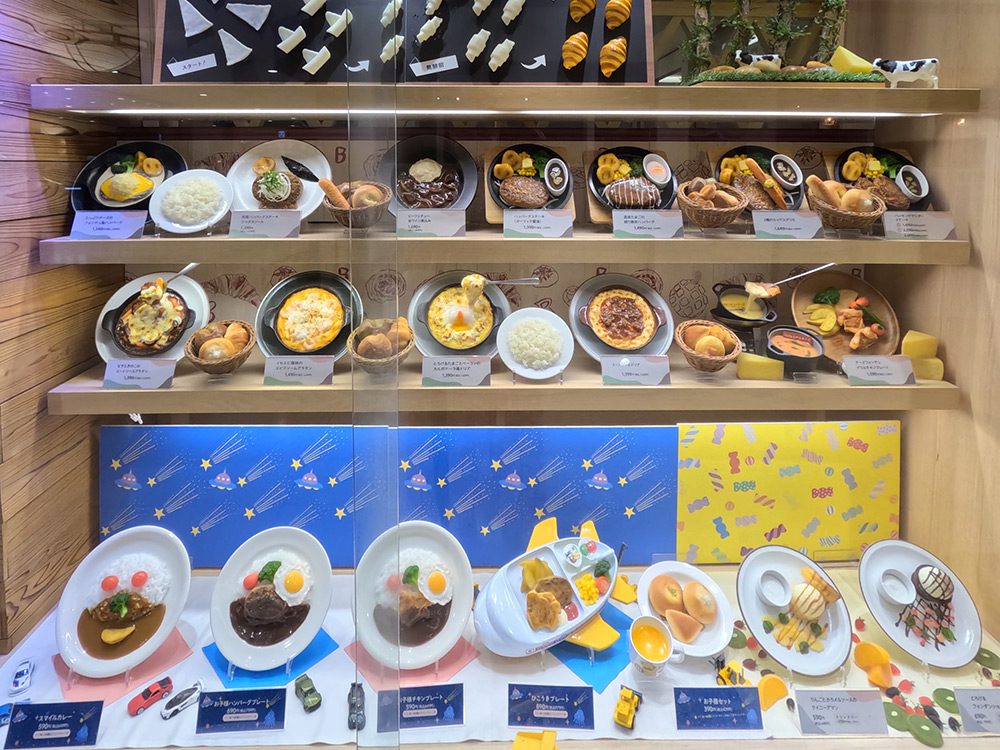 Kids menu food display on the bottom shelf of a window with cartoon-style decoration