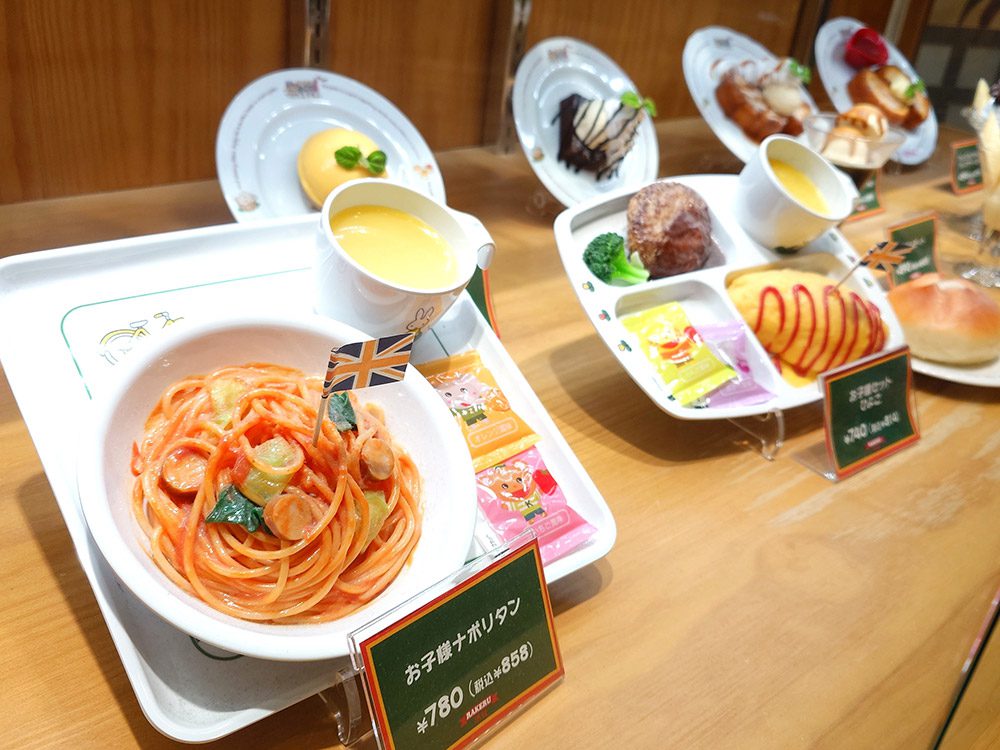 Two Japanese kids menu plates — omurice with a smiling ketchup face and an airplane-shaped dish with hamburger and rice — examples of family friendly restaurant marketing