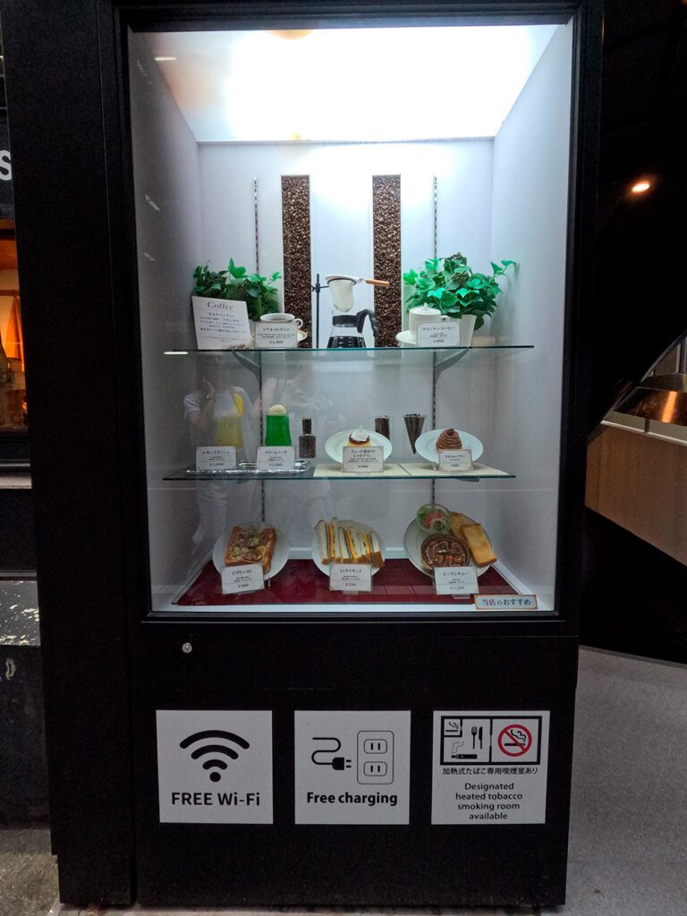 Common restaurant window display lighting mistake — top-only light flattens food and darkens lower shelves