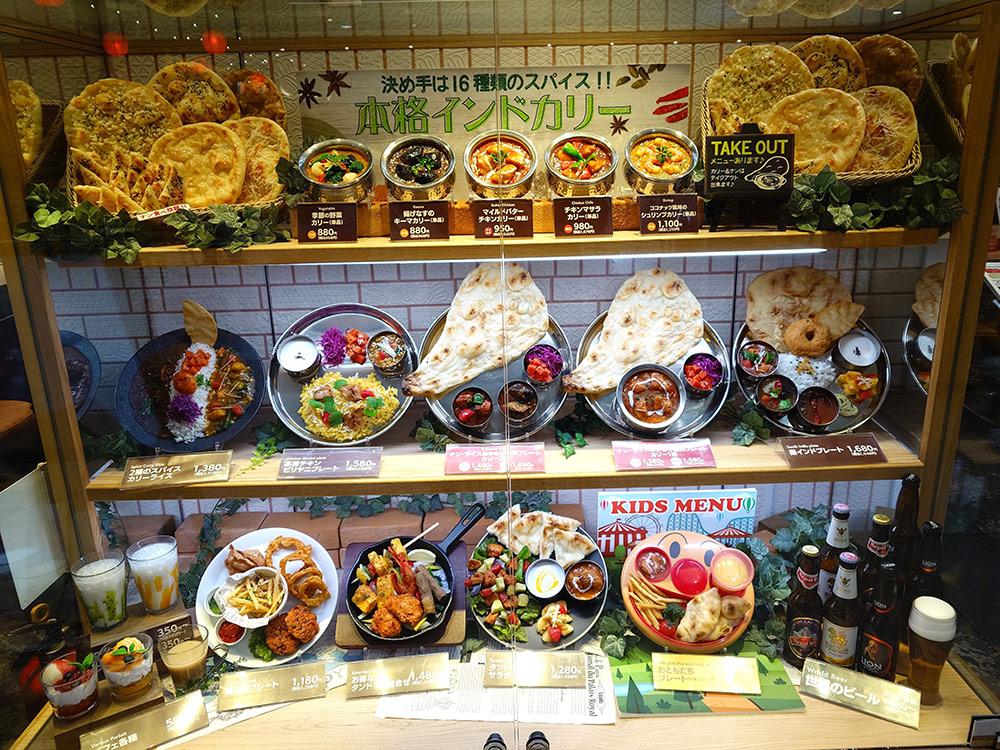 Asian cuisine displays grouped in an Indian restaurant window with naan, curry and thali