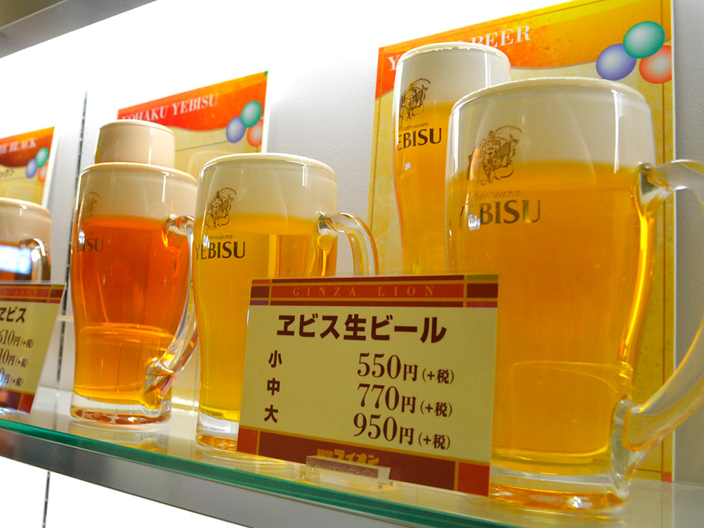 Draft beer replicas in three sizes with a price card, cafe window drinks