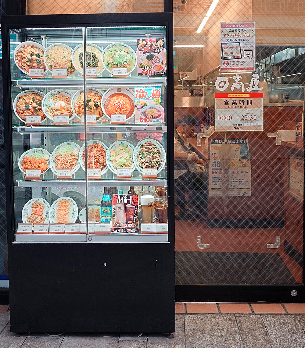 Chinese restaurant window display standing beside the entrance with ramen, gyoza and beer replicas