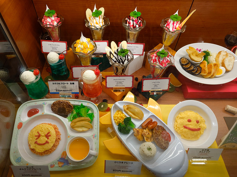 Kids meal set models with parfaits and colorful floats on the shelf above