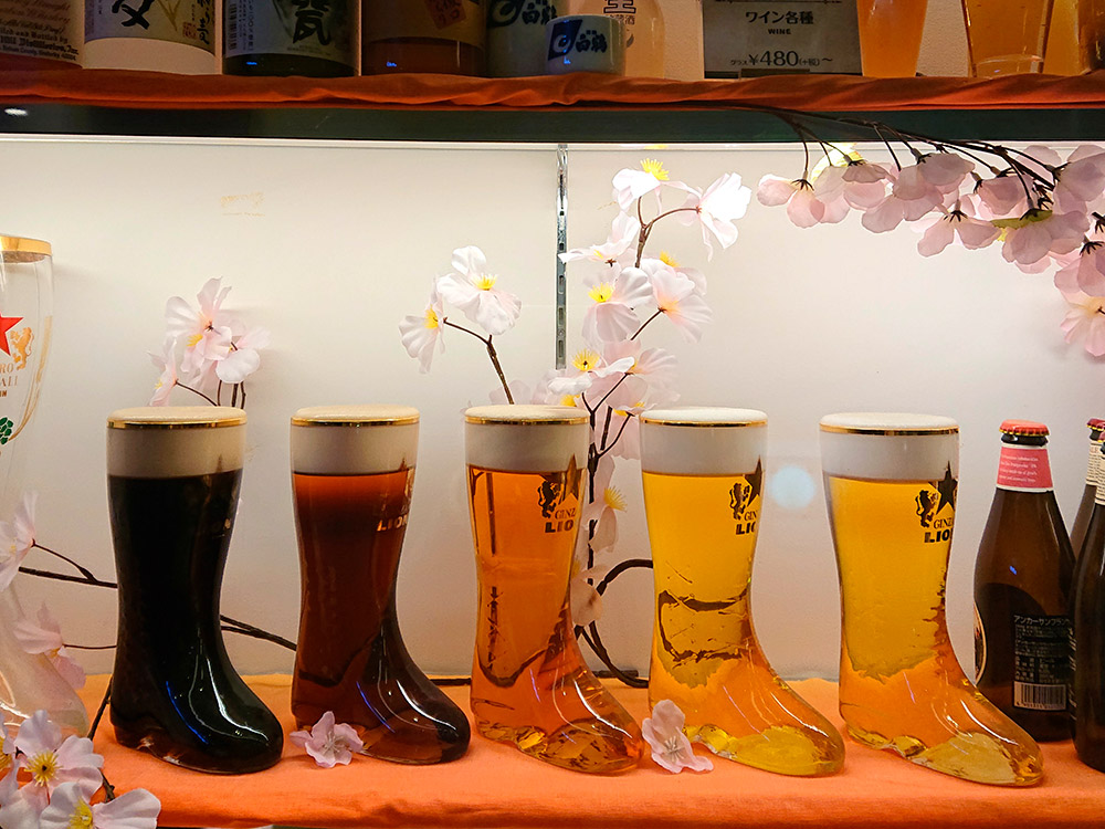 Five beer replicas in branded boot-shaped glasses, how to display drinks in a cafe window