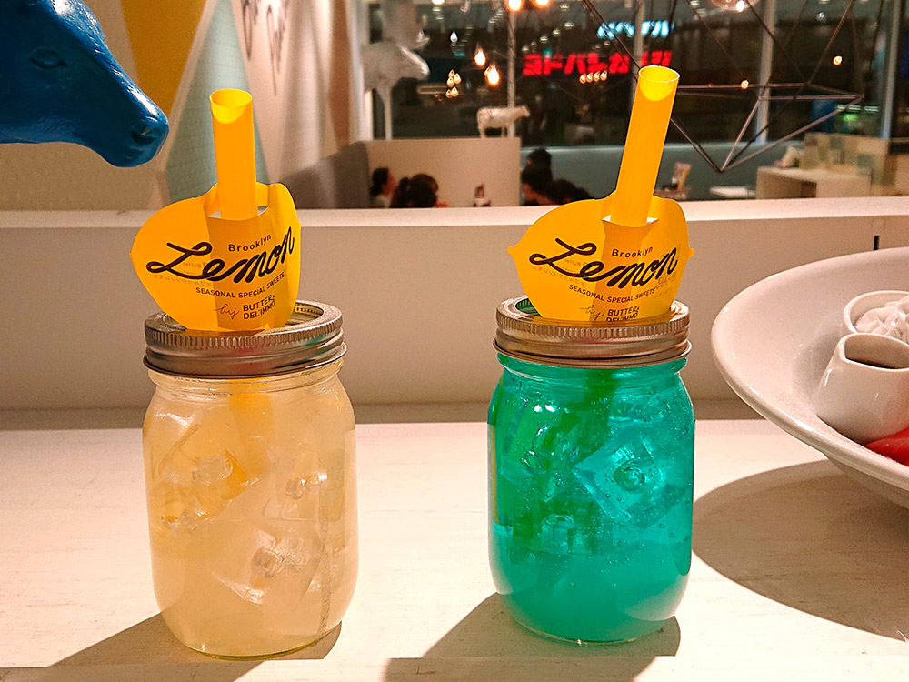Two lemonade silicone replicas in branded mason jars with straws in a cafe window