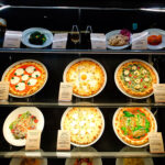 Italian restaurant window with pizza replicas tilted at forty five degrees
