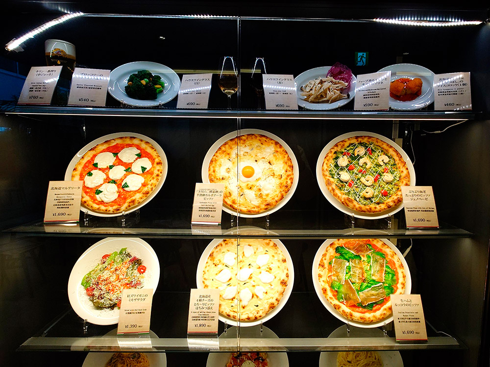 Italian restaurant window with pizza replicas tilted at forty five degrees