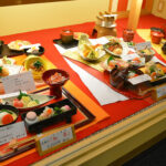 Japanese restaurant window display with red backdrop, kaiseki set replicas and price cards