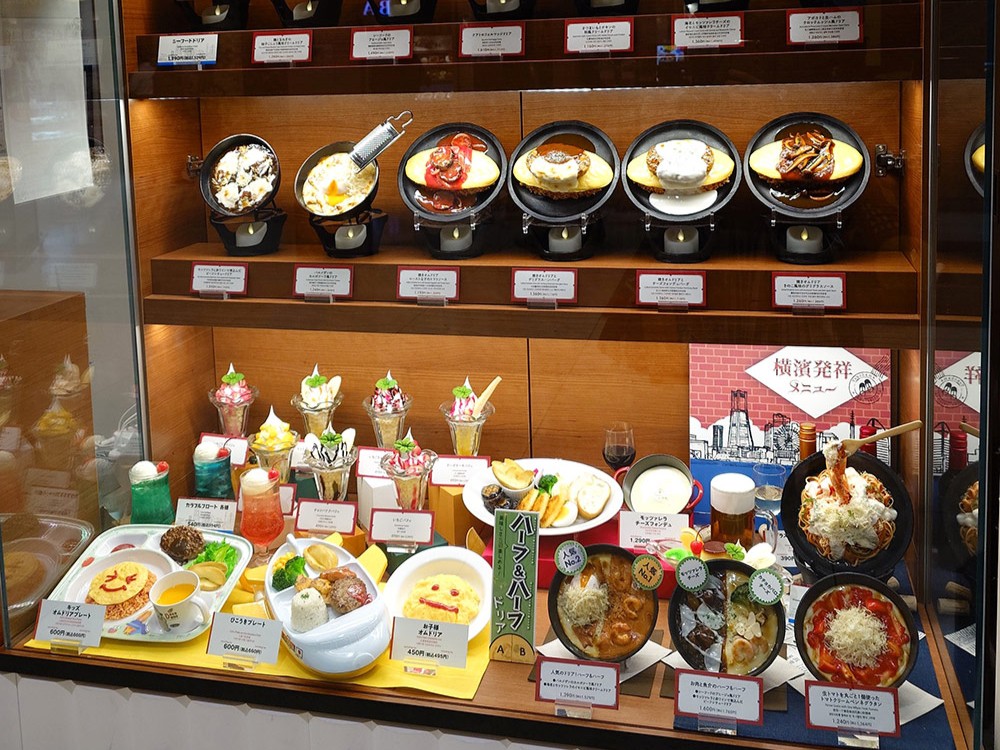 Kids meal replicas with smiley omelette rice on the lower shelf of a restaurant window
