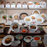 Restaurant window display lighting reaching only the upper shelves of a Chinese food case