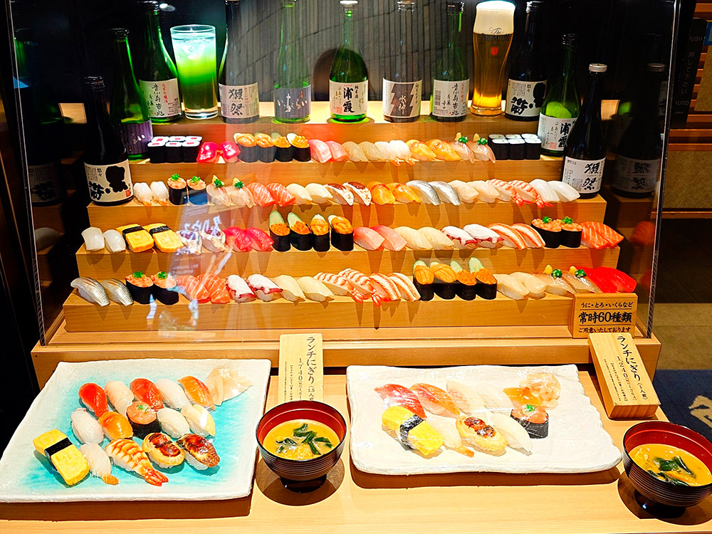 Paired nigiri fill a sushi replica display case showing the full range of toppings