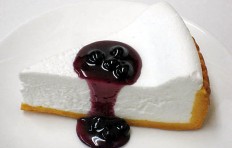 A replica of white cheesecake with bilberry sauce
