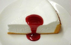 A replica of cheesecake with raspberry sauce